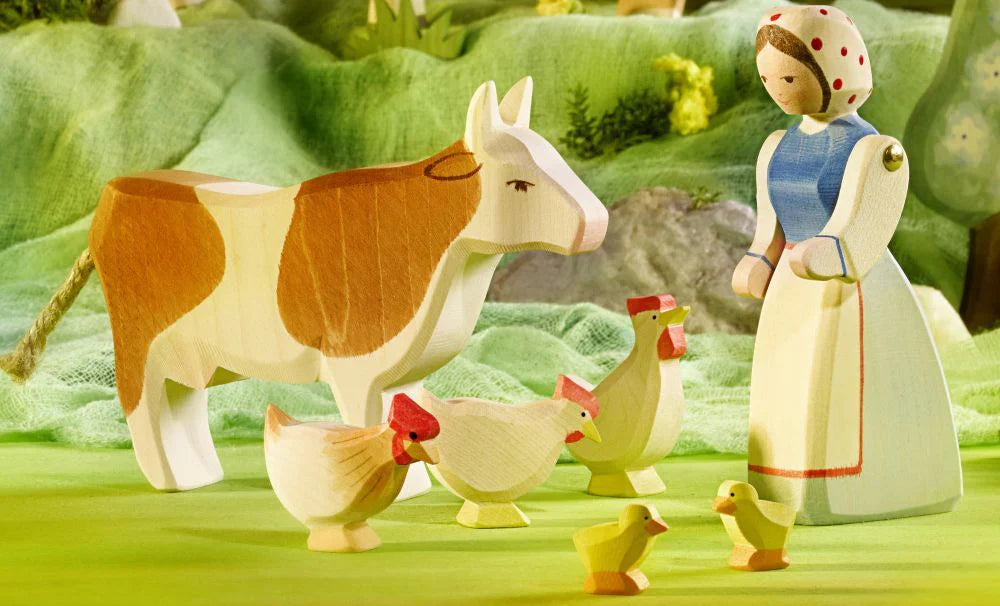 A farm scene replication with a farmer girl, cows, chickens and hens.